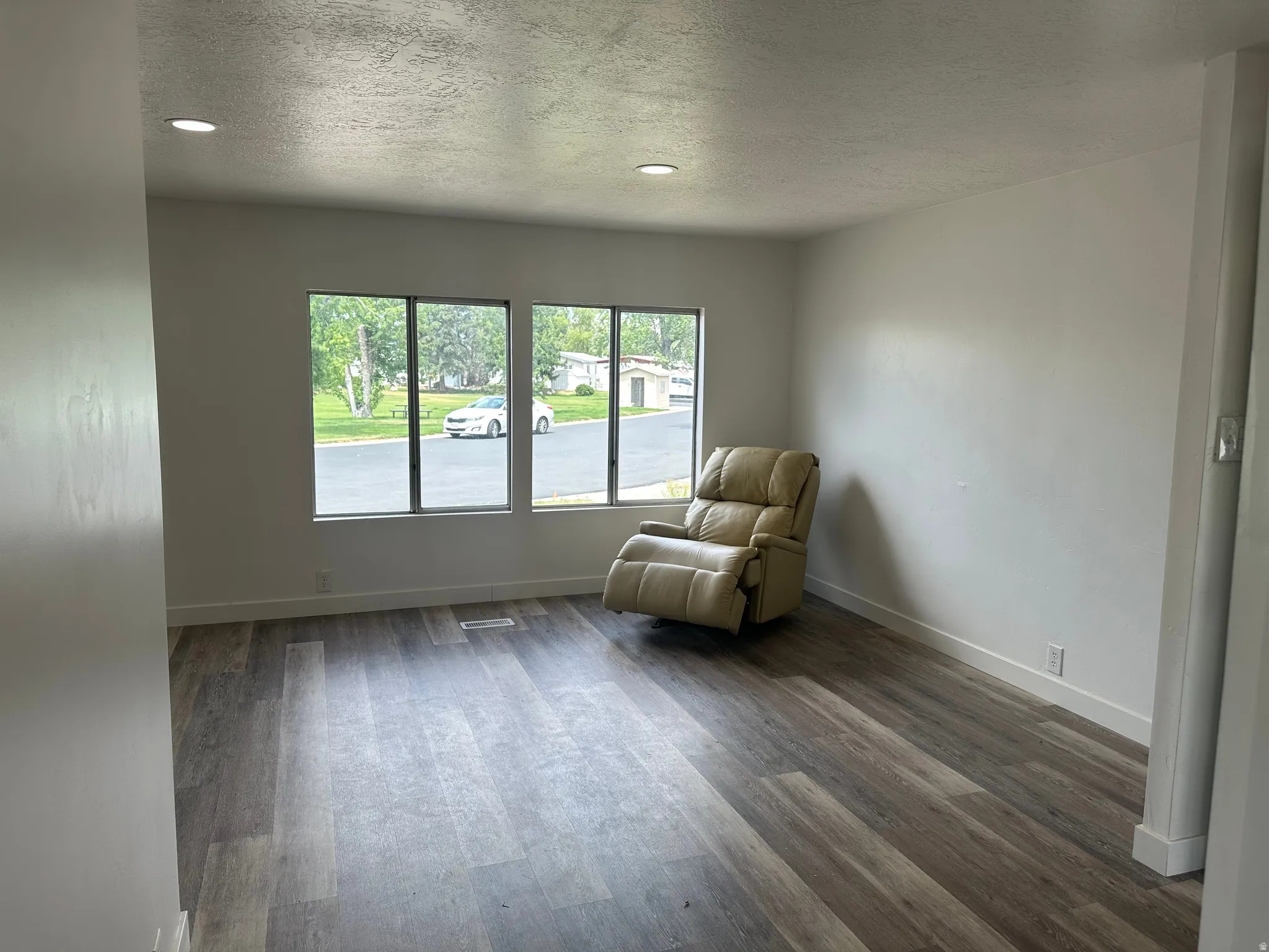 Spacious room featuring wood-finish flooring, white baseboards, and neutral wall paint