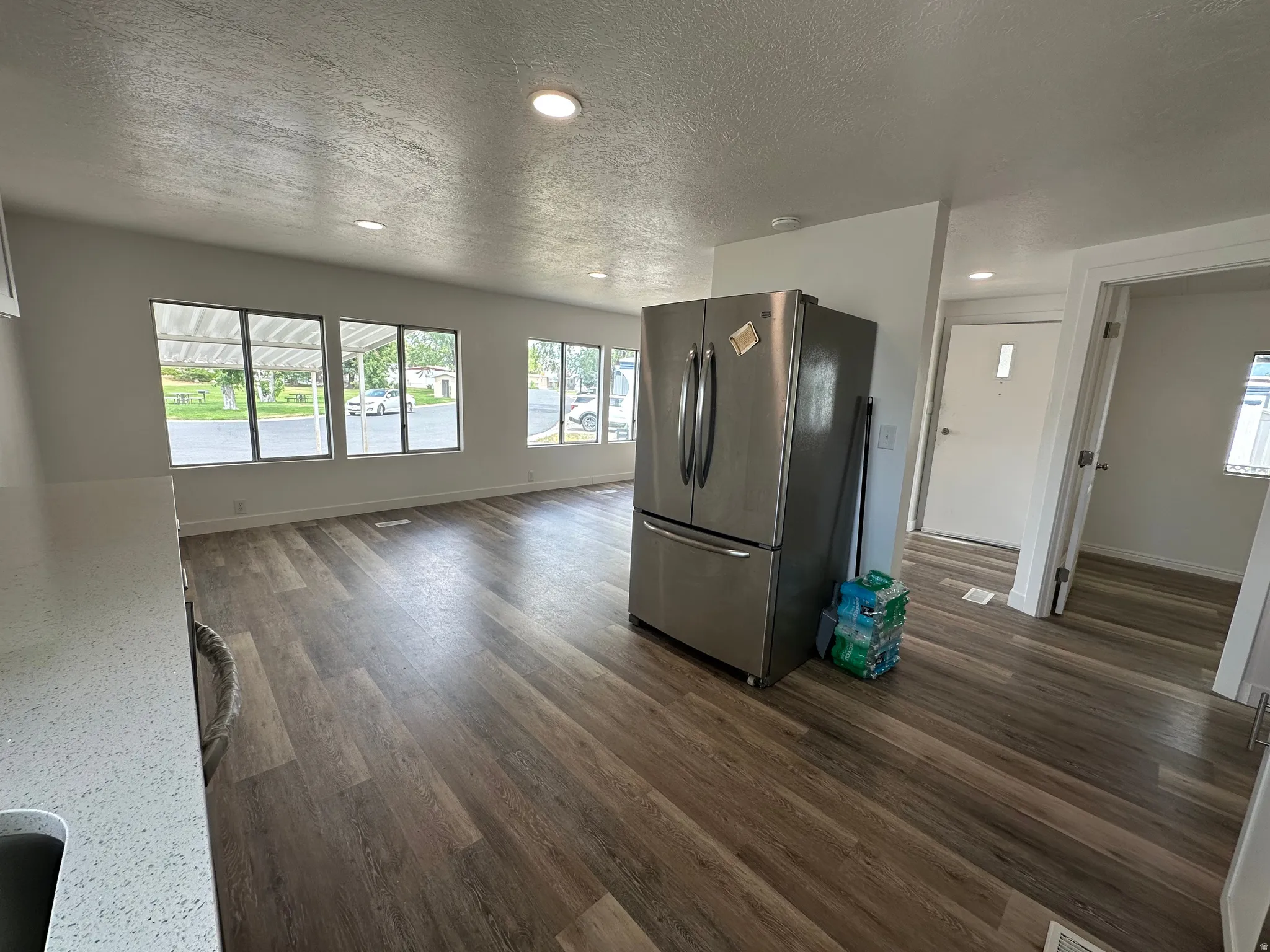 Open-concept living area featuring wood-finish flooring, recessed lighting, and multiple windows providing natural illumination