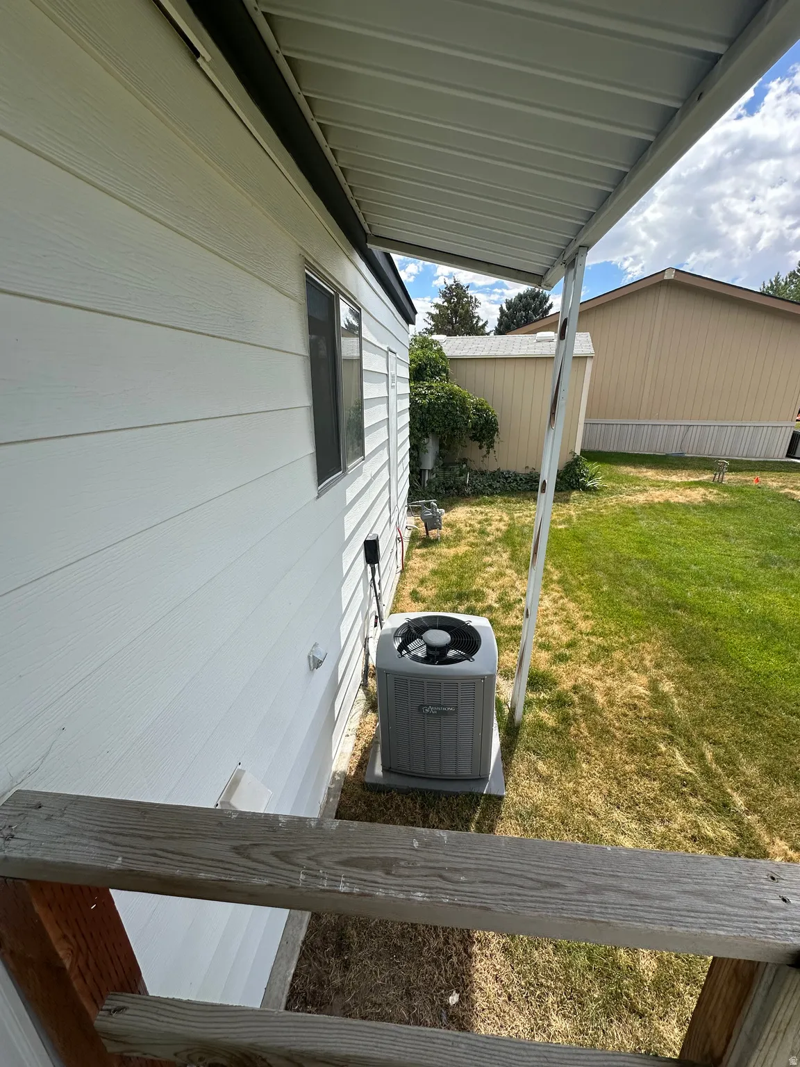 Side exterior with white horizontal siding and a covered patio area