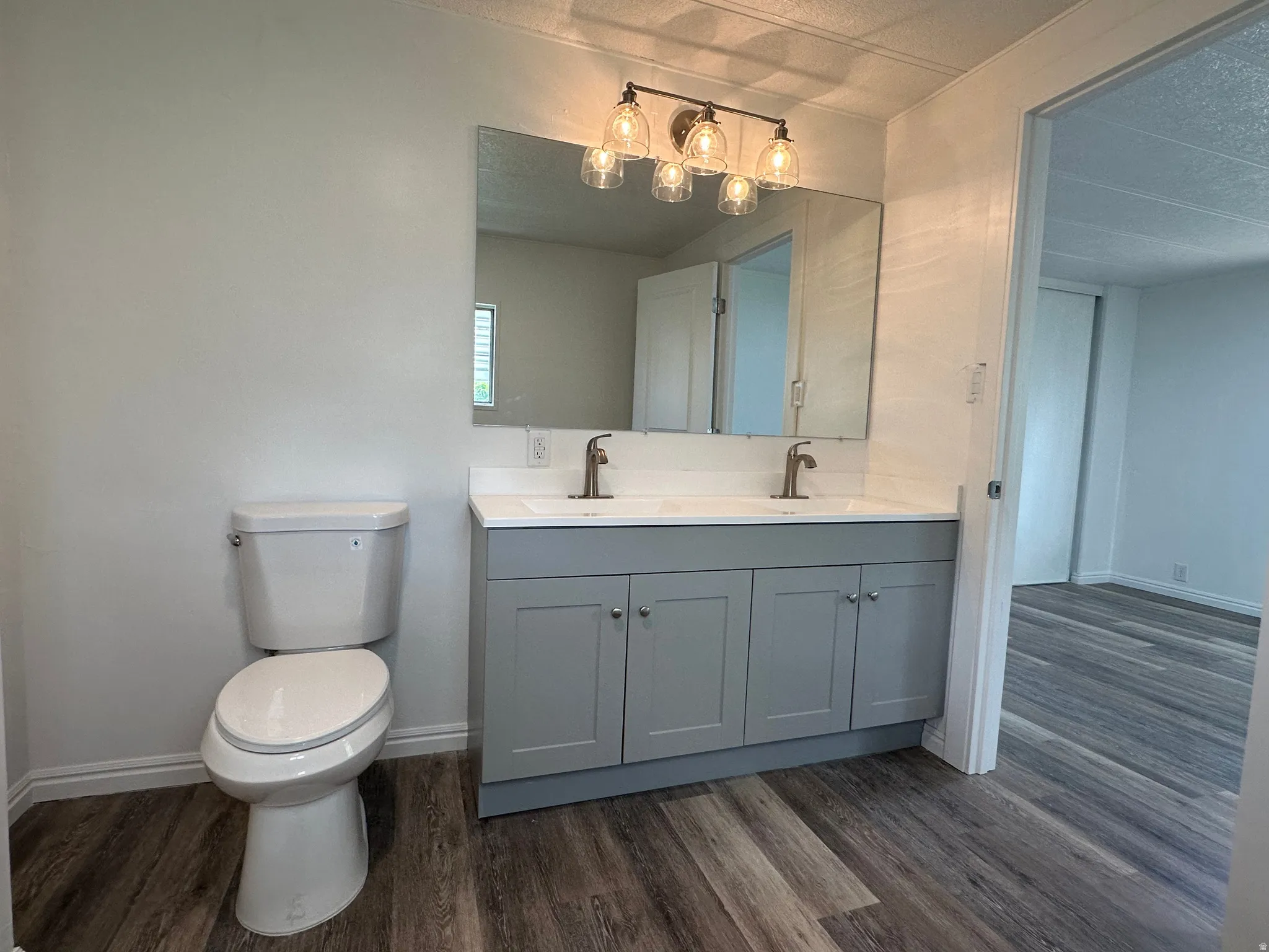 Bathroom featuring a dual vanity with a light gray cabinet, white countertop, and dual sinks with contemporary bronze faucets