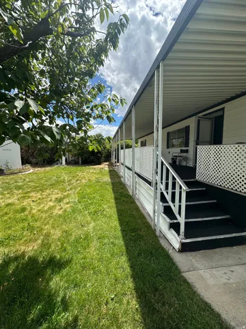 Expansive side yard with a manicured lawn leading to a covered porch entry