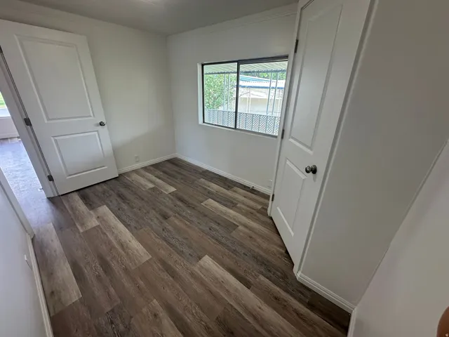 Room with wood-finish flooring, crisp white walls, and bright white trim
