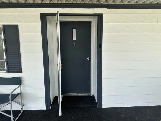 Front entry featuring a dark-colored main door with a rectangular window insert, complemented by a white storm door