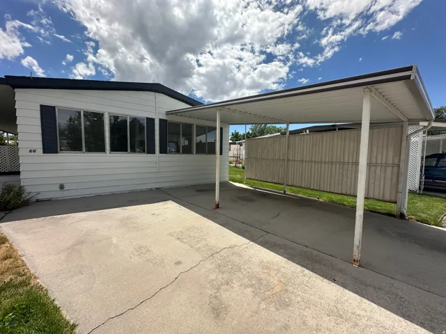 White siding exterior with dark shutters, featuring a covered carport and concrete driveway