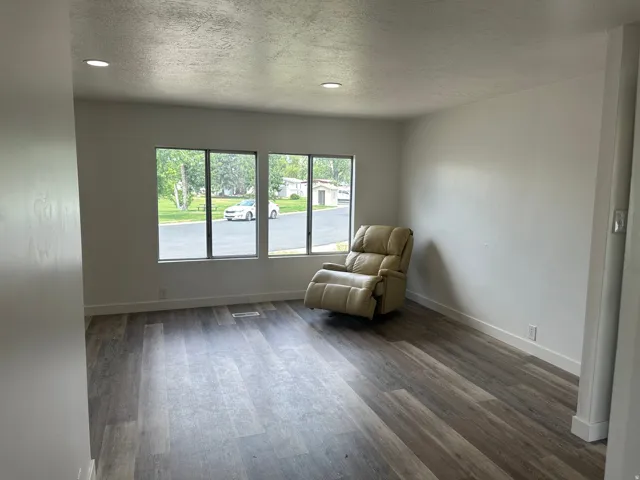 Spacious room featuring wood-finish flooring, white baseboards, and neutral wall paint