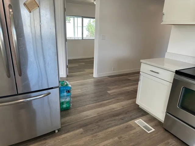 Modern kitchen area featuring stainless steel appliances, white cabinetry with silver hardware, and a light-toned countertop