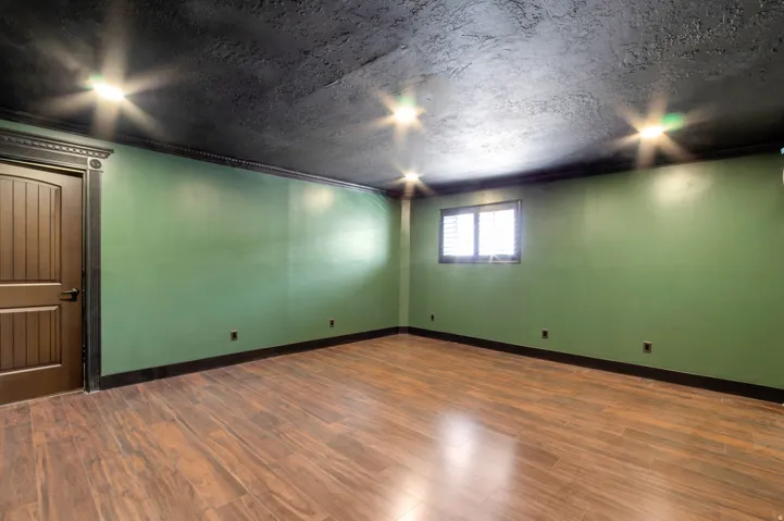 Spacious room featuring wood-finish flooring, recessed lighting, and a window with louvered blinds