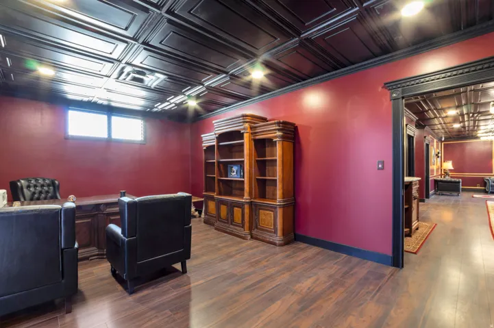Spacious room featuring wood-finish flooring, dark red walls, and a black coffered ceiling with recessed lighting
