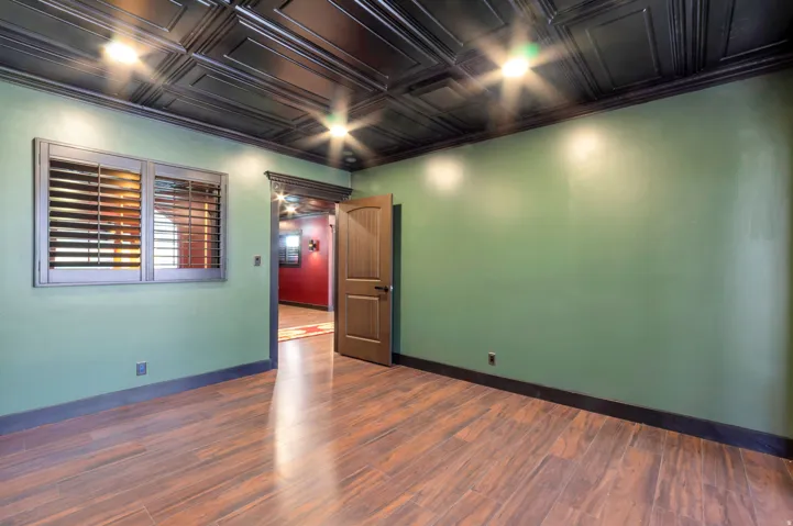 Room featuring a dark paneled ceiling with recessed lighting, green walls, and wood-finish flooring