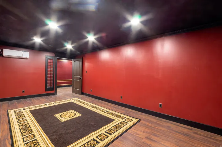 Spacious room featuring rich red walls, dark wood-finish flooring, and recessed ceiling lighting
