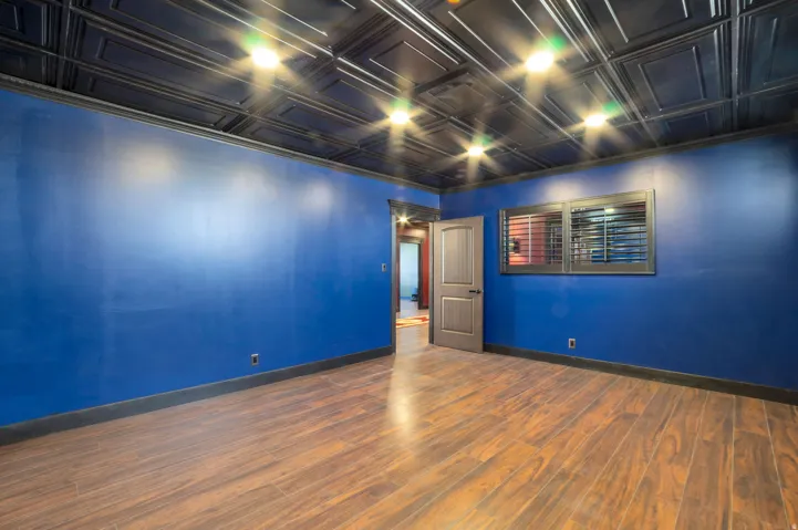 Spacious room featuring wood-finish flooring, a dark coffered ceiling with recessed lighting, and rich blue wall finishes