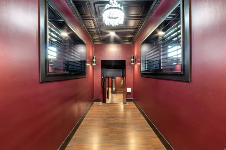 Hallway featuring wood-finish flooring, deep red walls, and a coffered ceiling with a chandelier