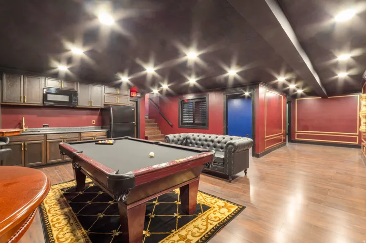 Recreation room featuring wood-finish flooring, a full wet bar with built-in cabinetry, a built-in microwave, and a full-size refrigerator