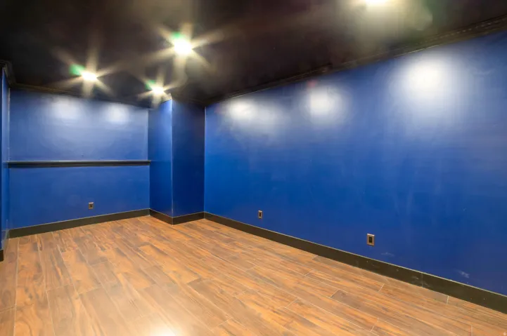 Room featuring wood-finish flooring, dark blue walls, black trim, and recessed ceiling lighting