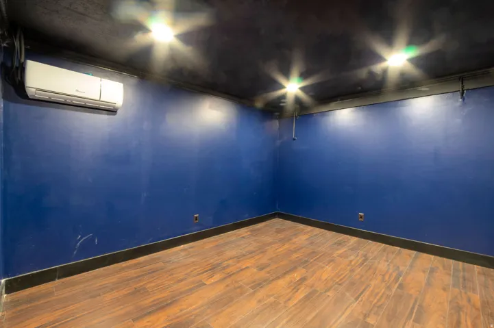 Interior room featuring wood-finish flooring, a wall-mounted mini-split system, recessed ceiling lighting, and dark blue wall finishes with black trim