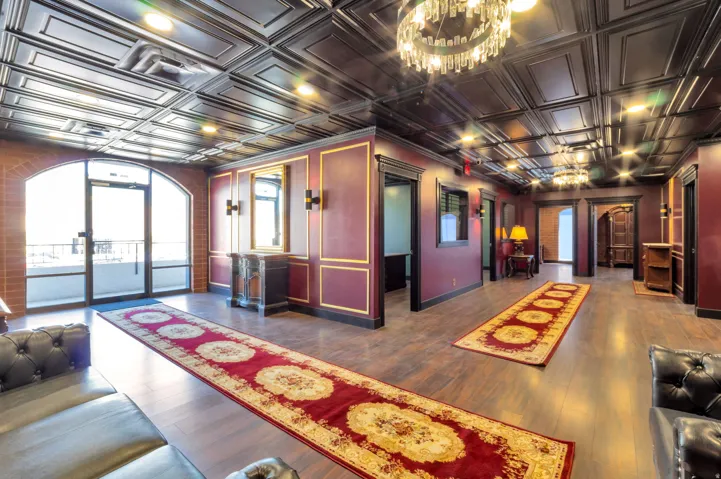 Spacious interior featuring a coffered ceiling, wood-finish flooring, and ornate chandeliers