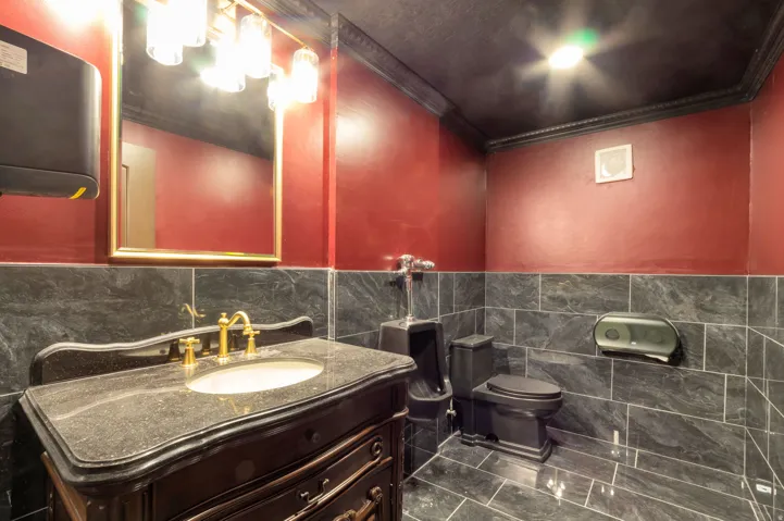 Vanity with a dark stone countertop and brass-finish fixtures