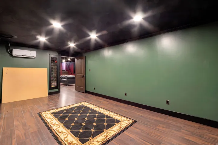 Spacious room featuring wood-finish flooring, dark green walls, recessed lighting, and a mini-split air conditioning unit