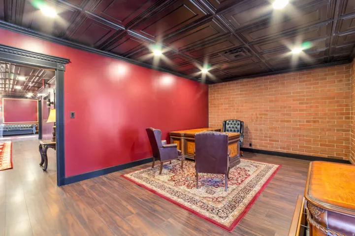 Rich wood-finish flooring complements a dark embossed ceiling and brick accent wall