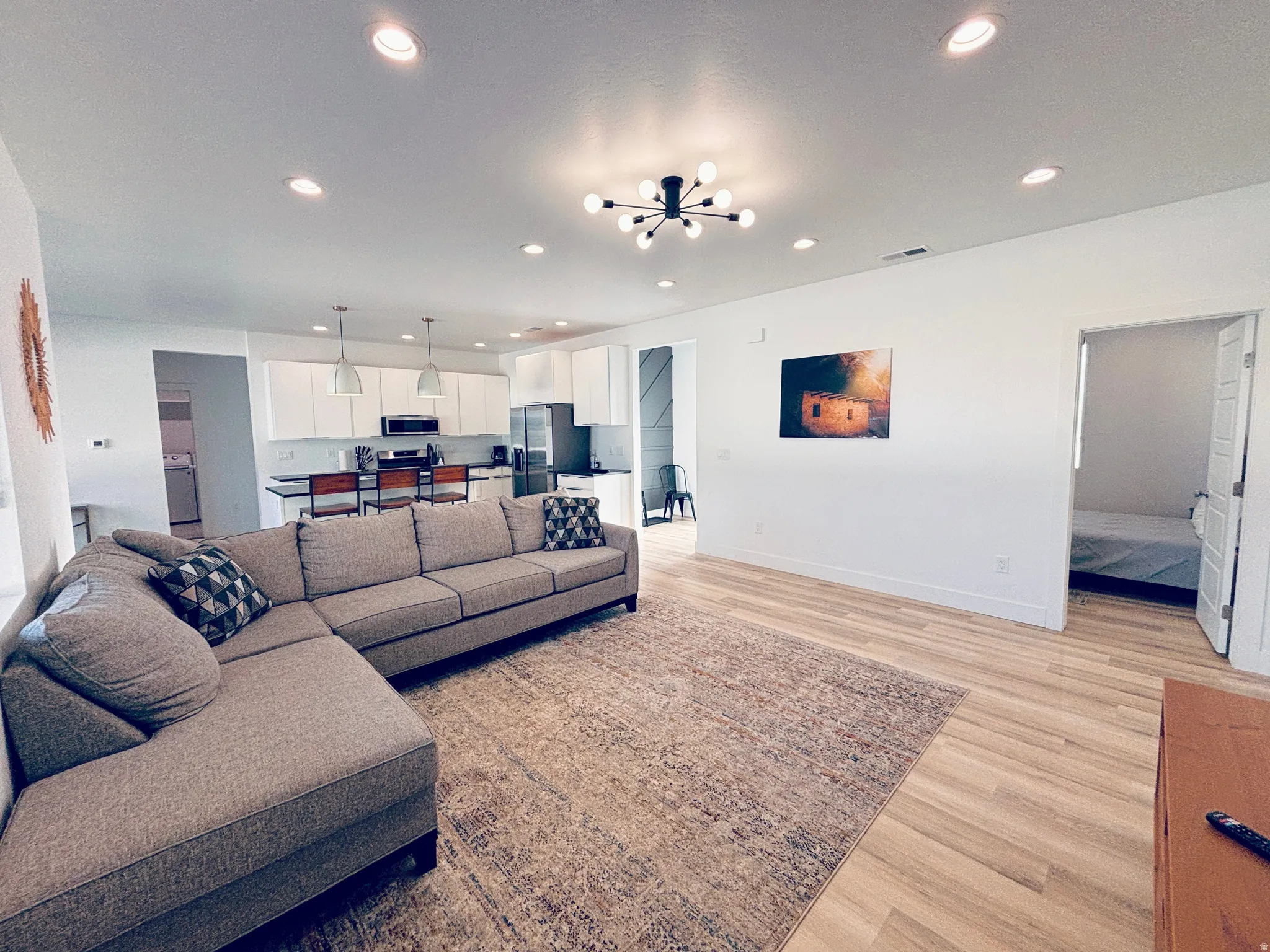 Open-concept living space featuring wood-finish flooring, recessed lighting, and a contemporary sputnik chandelier