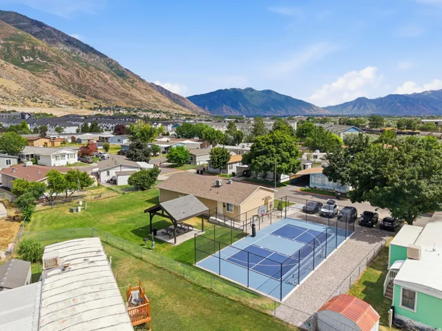 Exterior amenities featuring a fenced sports court, covered patio structure, and a large lawn area