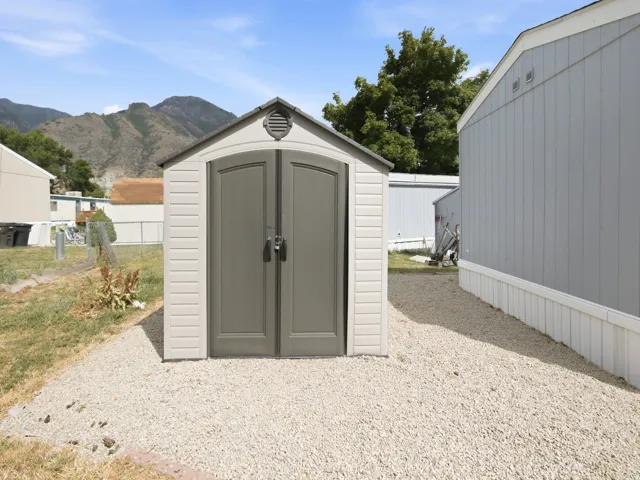 Gable-roof storage shed with double doors situated on a gravel pad