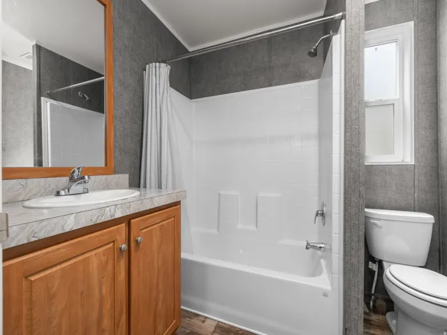 Bathroom featuring a wood-finish vanity with a light-toned countertop, a white drop-in sink, and a chrome faucet