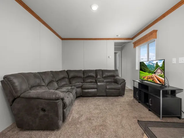 Living area with light gray walls, brown trim, and wall-to-wall carpeting