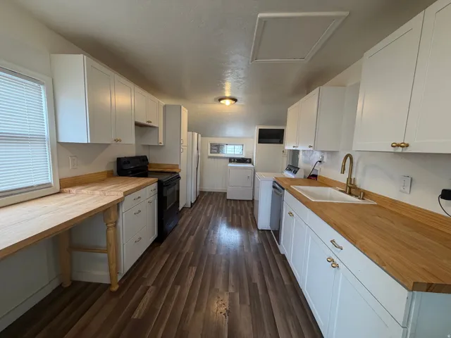 Kitchen featuring wood-finish flooring, white cabinetry with gold-tone hardware, wood countertops, and a white sink with a gooseneck faucet