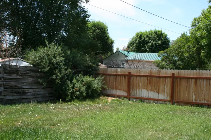 Grassed yard featuring a wood privacy fence and mature landscaping