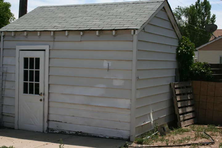 Detached ancillary structure featuring horizontal siding and a gabled roof with composition shingles