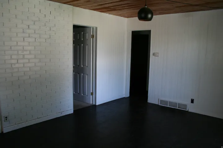 Interior space featuring dark flooring, white paneled walls, and a painted brick accent wall