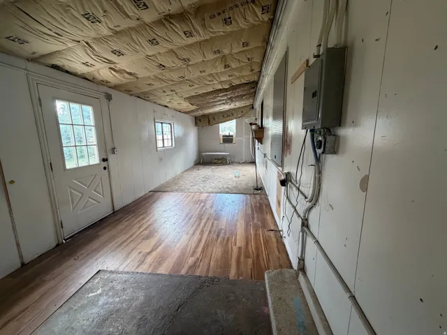 Spacious room featuring wood-finish flooring, white panel walls, and an exterior door with glass panes