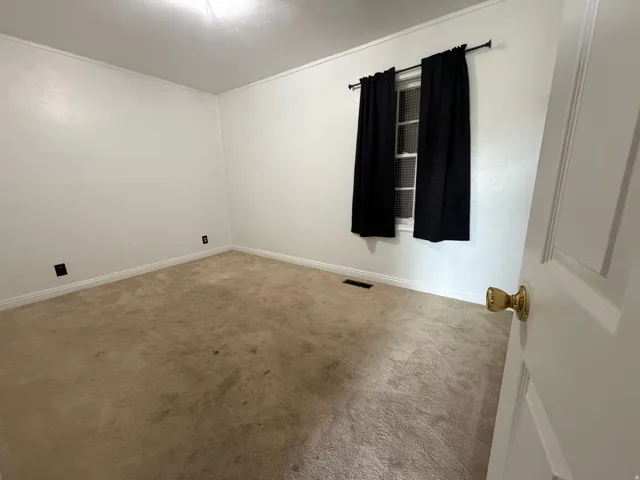 Room featuring carpet flooring, white walls, and a window with black curtains