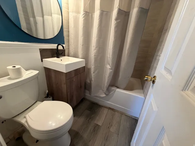 Modern bathroom featuring a compact wood-finish vanity with an integrated basin and matte black faucet