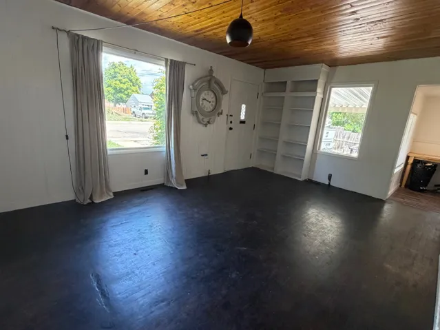 Interior room featuring dark wood-finish flooring, white paneled walls, and a wood-paneled ceiling