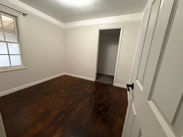 Room featuring dark wood-finish flooring, white baseboards, and light-colored walls