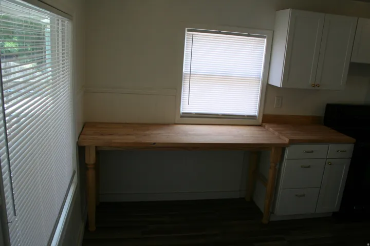 Butcher block style countertops with white cabinetry and dark wood-finish flooring