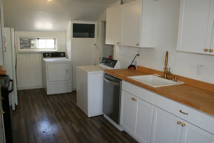 Kitchenette featuring white cabinetry with gold-tone hardware, wood-finish countertops, and a white inset sink with a gold-tone faucet