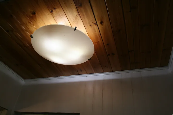 Wood-finish plank ceiling with a flush-mount overhead light fixture