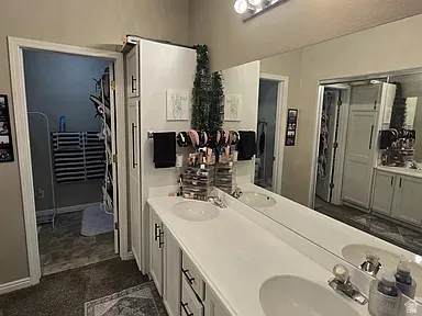 Bathroom vanity featuring dual under-mount sinks, white countertops, and white cabinetry with black hardware