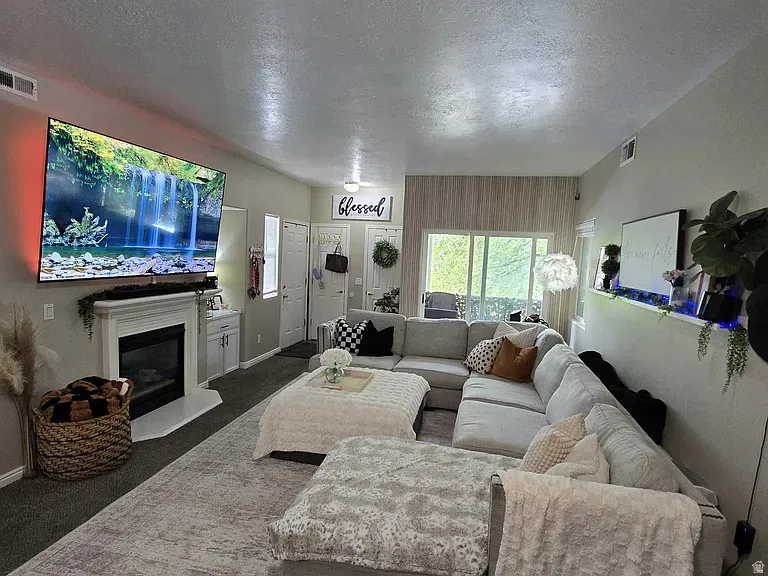 Spacious living area featuring a fireplace with a white mantel, an integrated wall-mounted media center, and a large sliding glass door