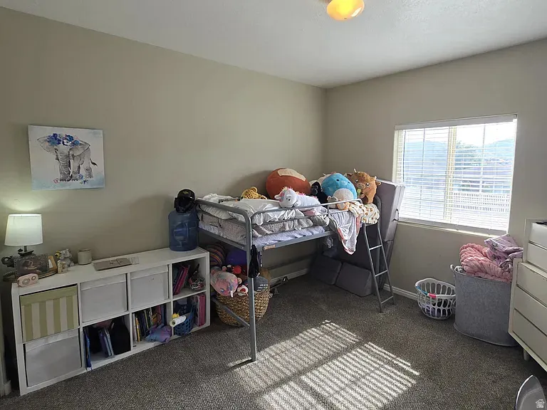 Carpeted room with a window featuring horizontal blinds, recessed baseboards, and a ceiling-mounted light fixture