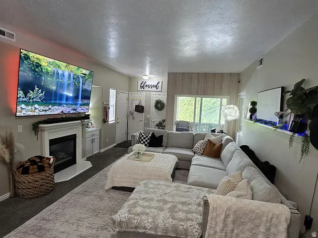 Spacious living area featuring a fireplace with a white mantel, an integrated wall-mounted media center, and a large sliding glass door