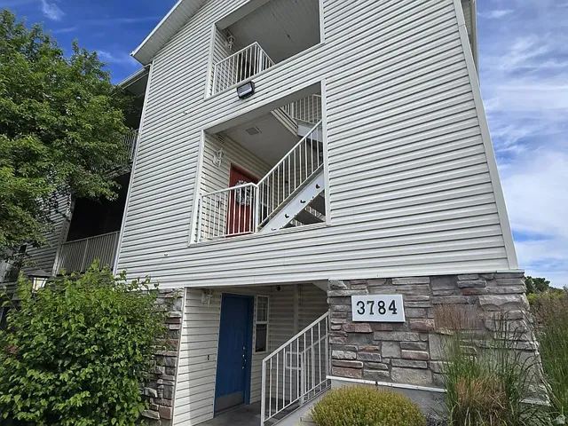 Multi-story exterior featuring horizontal siding and a stone veneer foundation
