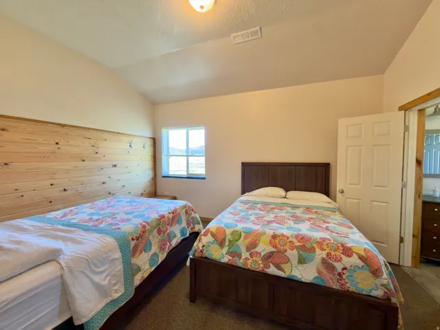 Bedroom with vaulted ceiling, wood-finish accent wall, and a multi-pane window