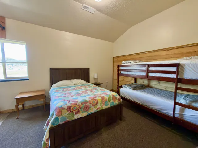 Room featuring a window with a mountain backdrop, vaulted ceiling, and textured carpet flooring