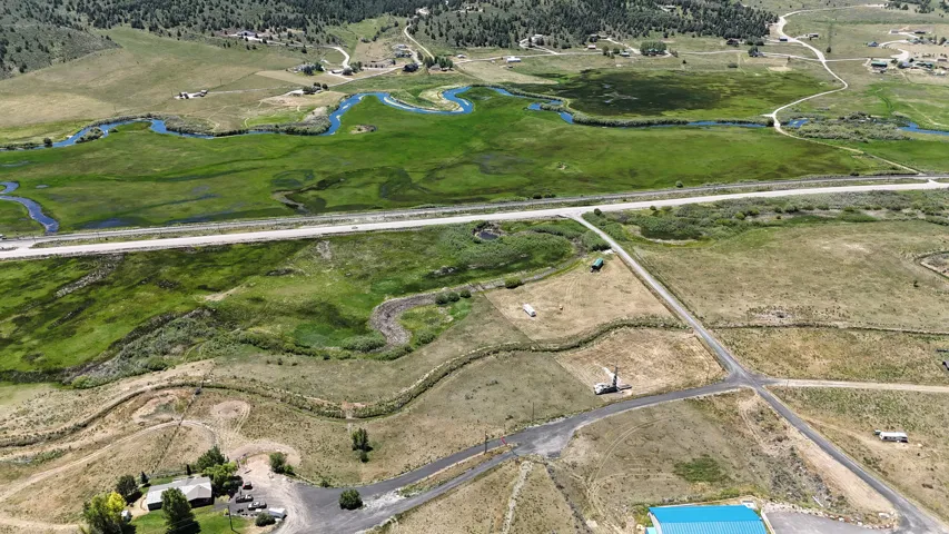 Expansive aerial landscape featuring a winding river, verdant marshland, and scattered residential properties