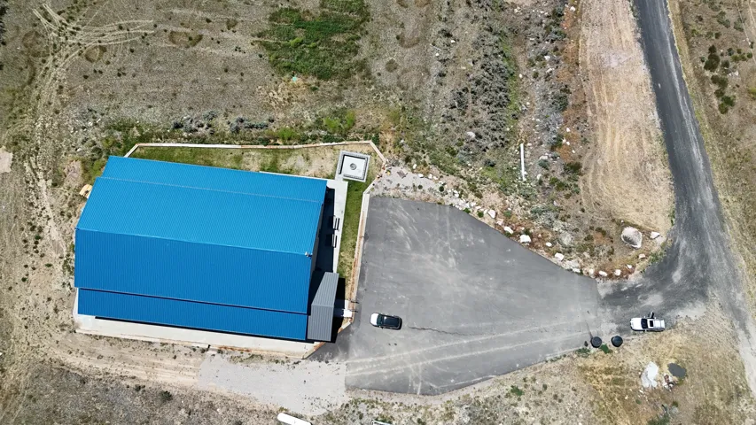 Property featuring a blue metal roof and a large paved driveway