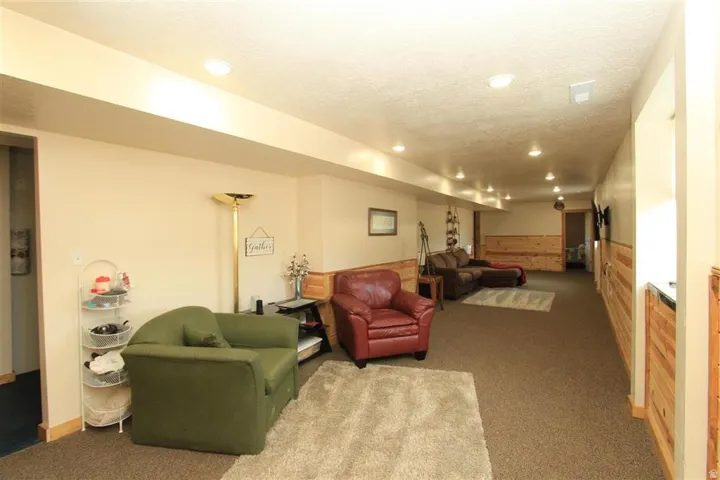 Spacious room featuring neutral painted walls, recessed lighting, carpet flooring, and a wood-paneled accent wall